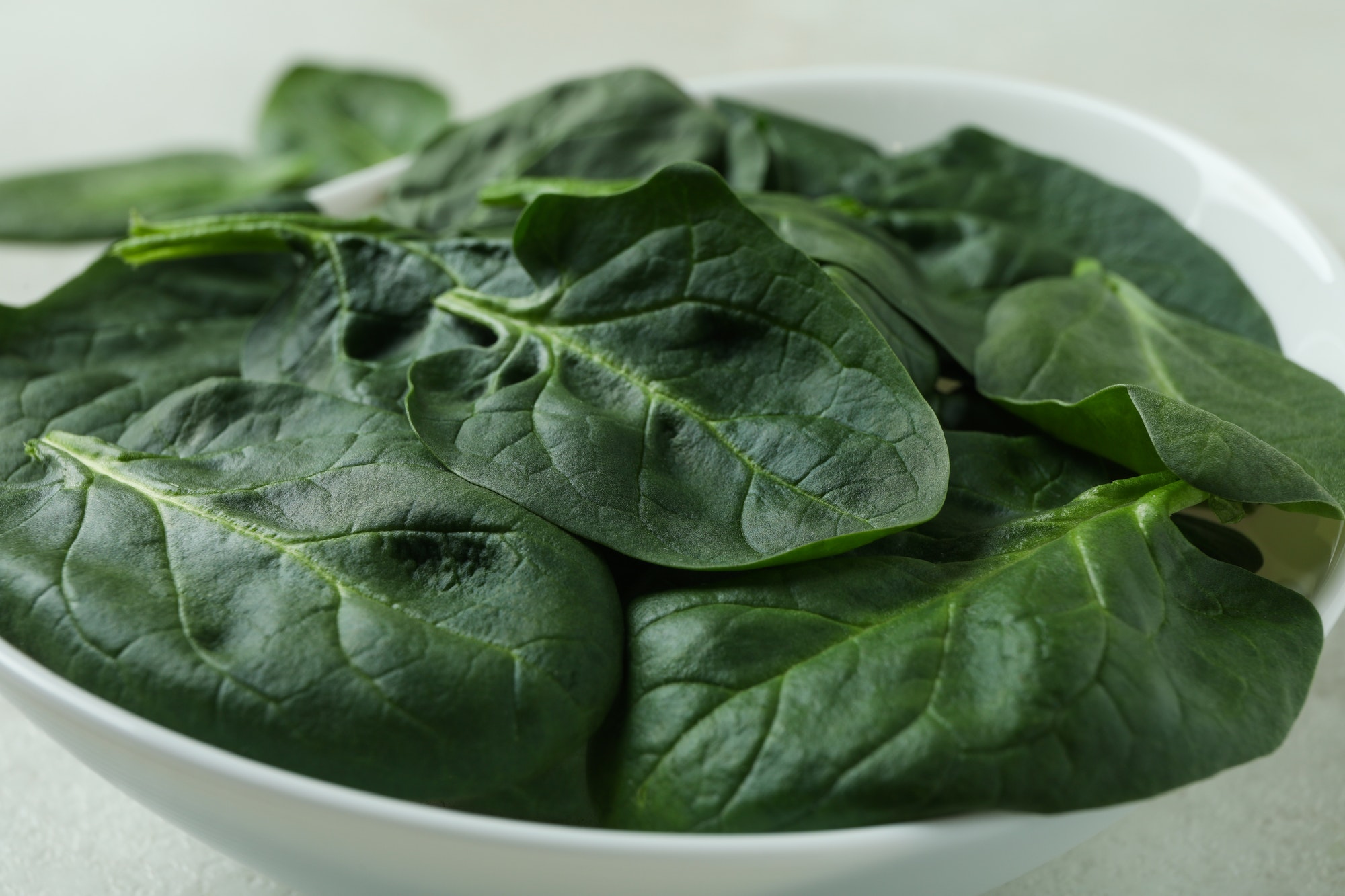 Bowl of fresh raw spinach, close up