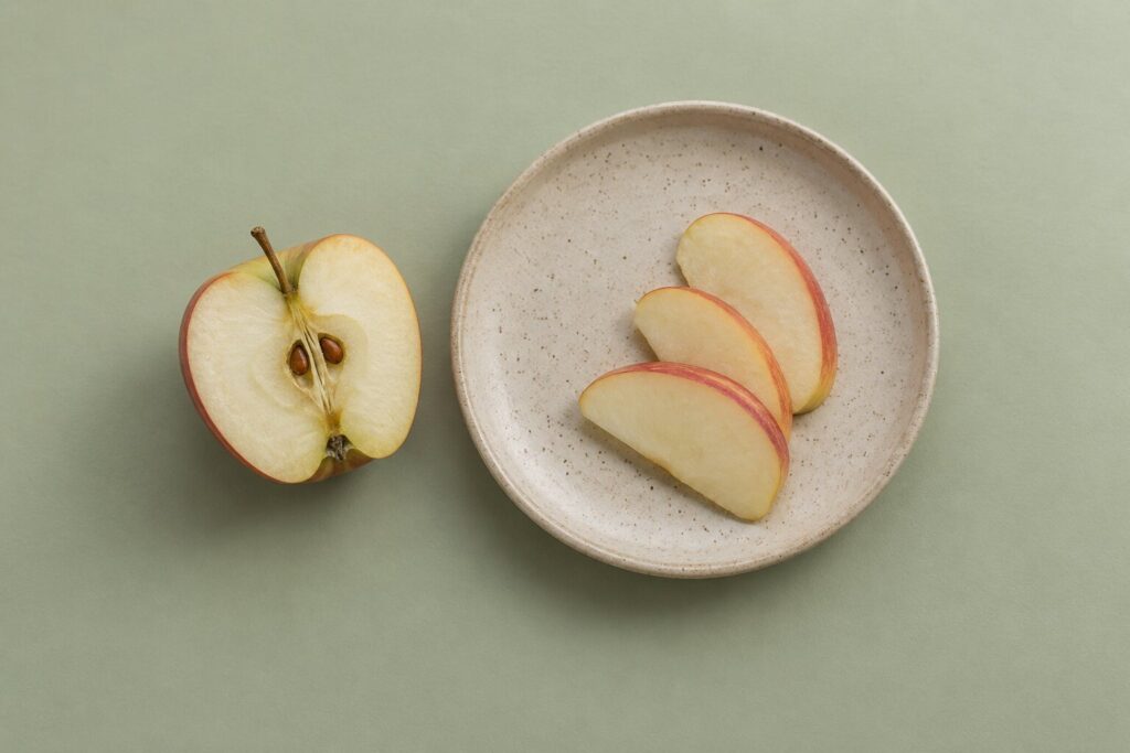Can Dogs Eat Apples? 1 An apple core with visible seeds sits apart from thin apple slices on a stoneware plate.