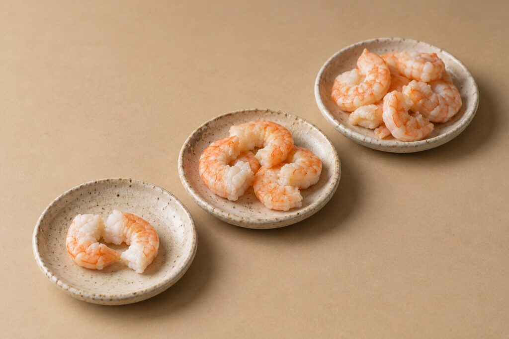 Can Dogs Eat Shrimp? 2 Three small dishes hold increasing portions of cut cooked shrimp pieces