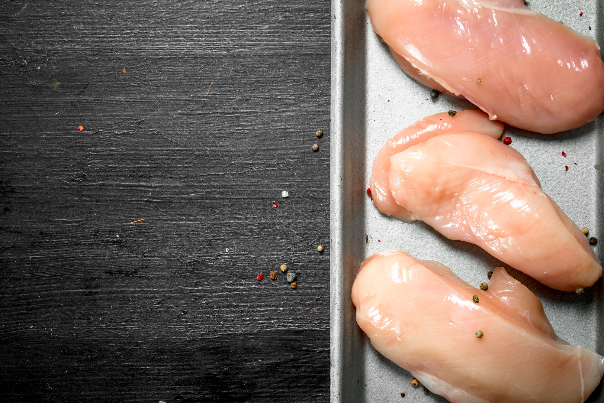 Raw chicken fillets on the tray.
